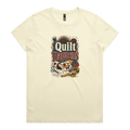 A pale butter yellow short-sleeve crewneck t-shirt featuring a colorful graphic print on the front with the text 'Quilt Happens' surrounded by quilting tools and fabrics.