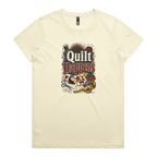 A pale butter yellow short-sleeve crewneck t-shirt featuring a colorful graphic print on the front with the text 'Quilt Happens' surrounded by quilting tools and fabrics.