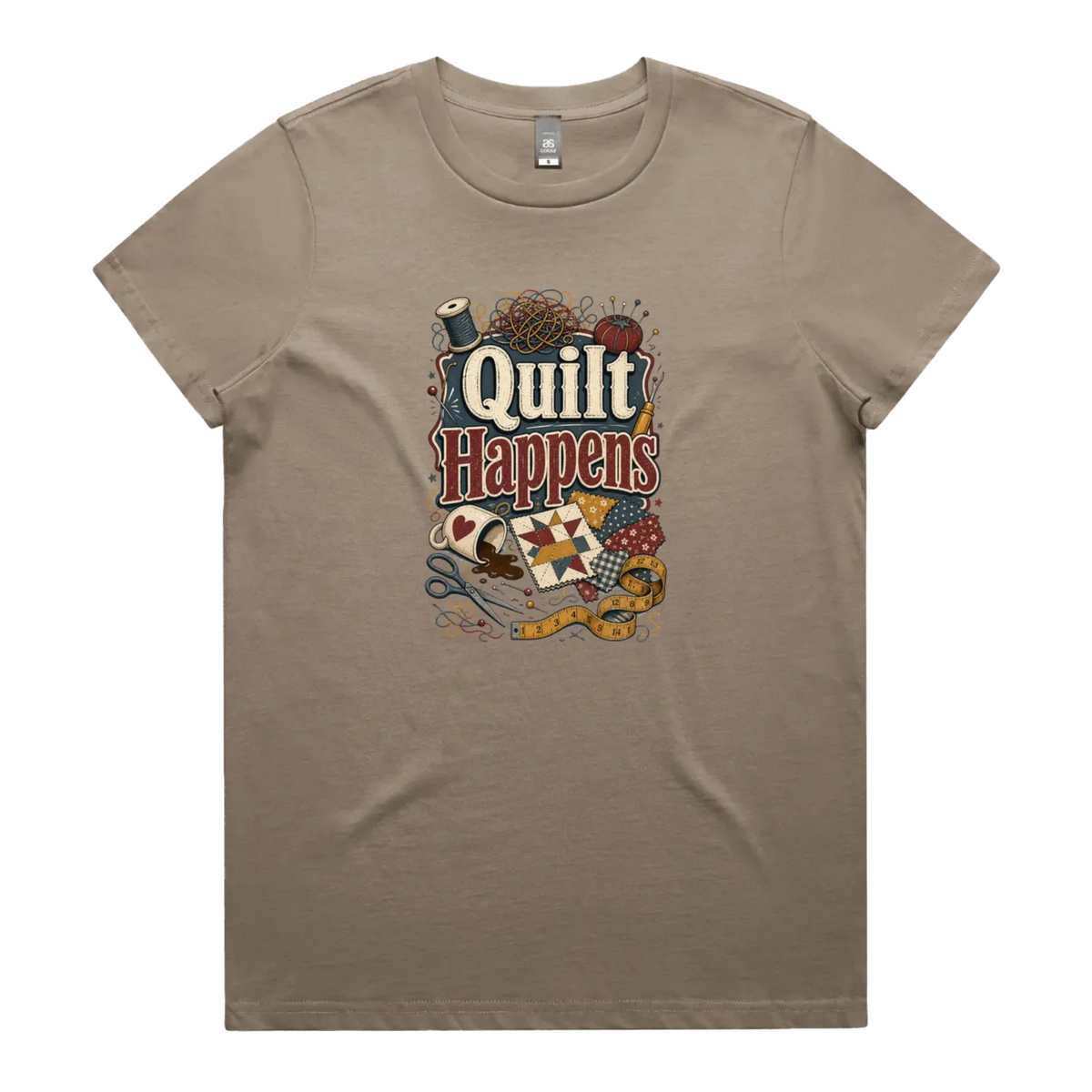 A mushroom brown short-sleeve crewneck t-shirt featuring a colorful graphic print on the front with the text 'Quilt Happens' surrounded by quilting tools and fabrics.