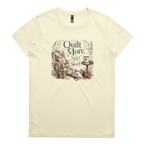 A pale butter yellow short-sleeve crewneck t-shirt featuring a vintage-style graphic on the front with the text 'Quilt More, Sip Slowly' surrounding an illustration of a quilted armchair, floral details, and sewing tools.
