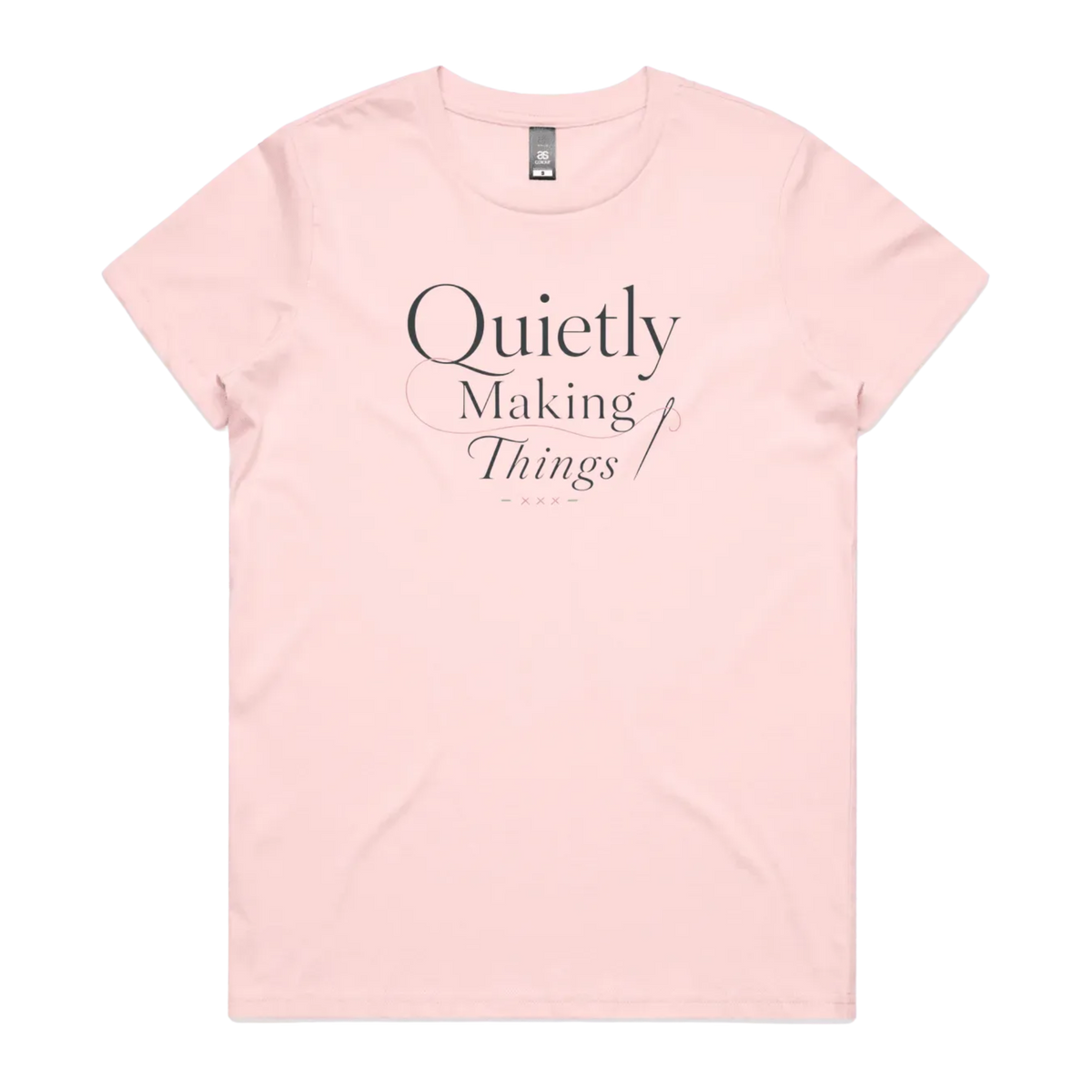 A pale pink short-sleeve crewneck t-shirt with a dark gray text graphic on the front reading 'Quietly Making Things' with needle and thread accents.