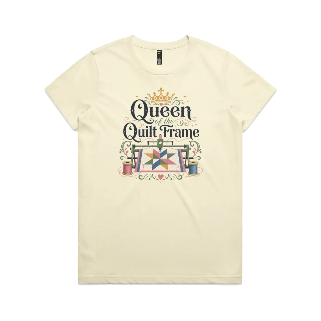 A pale butter yellow short-sleeve t-shirt with a graphic print on the front that reads 'Queen of the Quilt Frame' in black script, decorated with a gold crown, a quilt design, and spools of thread.