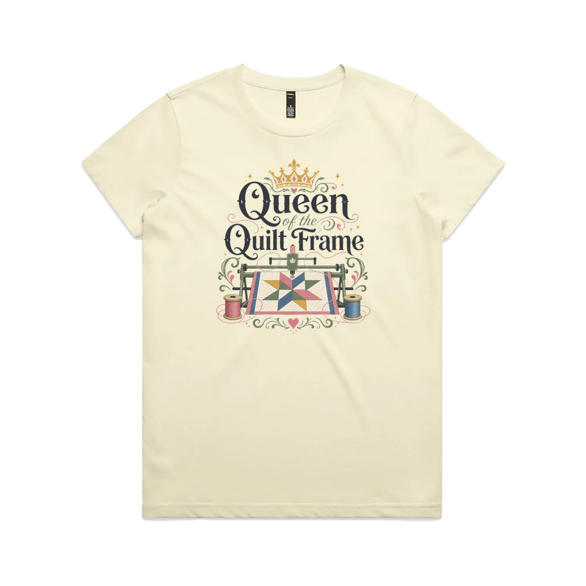A pale butter yellow short-sleeve t-shirt with a graphic print on the front that reads 'Queen of the Quilt Frame' in black script, decorated with a gold crown, a quilt design, and spools of thread.