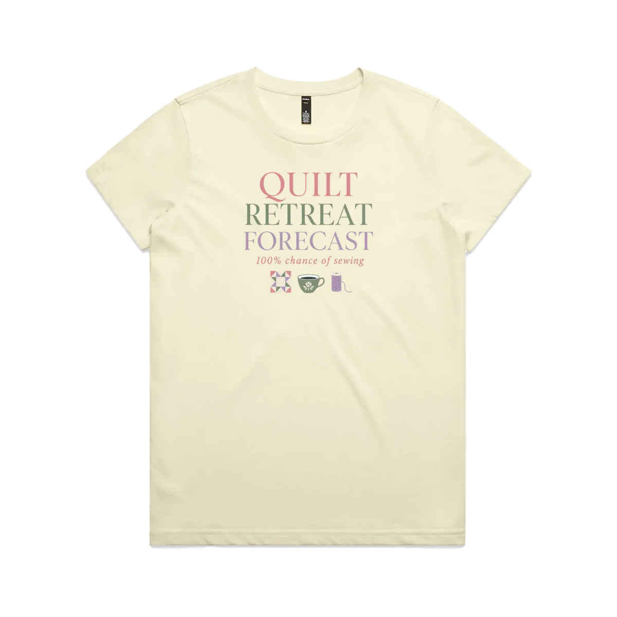 A pale butter yellow short-sleeve crewneck t-shirt featuring a graphic print on the front that reads 'QUILT RETREAT FORECAST, 100% chance of sewing' in pink, green, and white lettering, with small sewing-themed icons below.