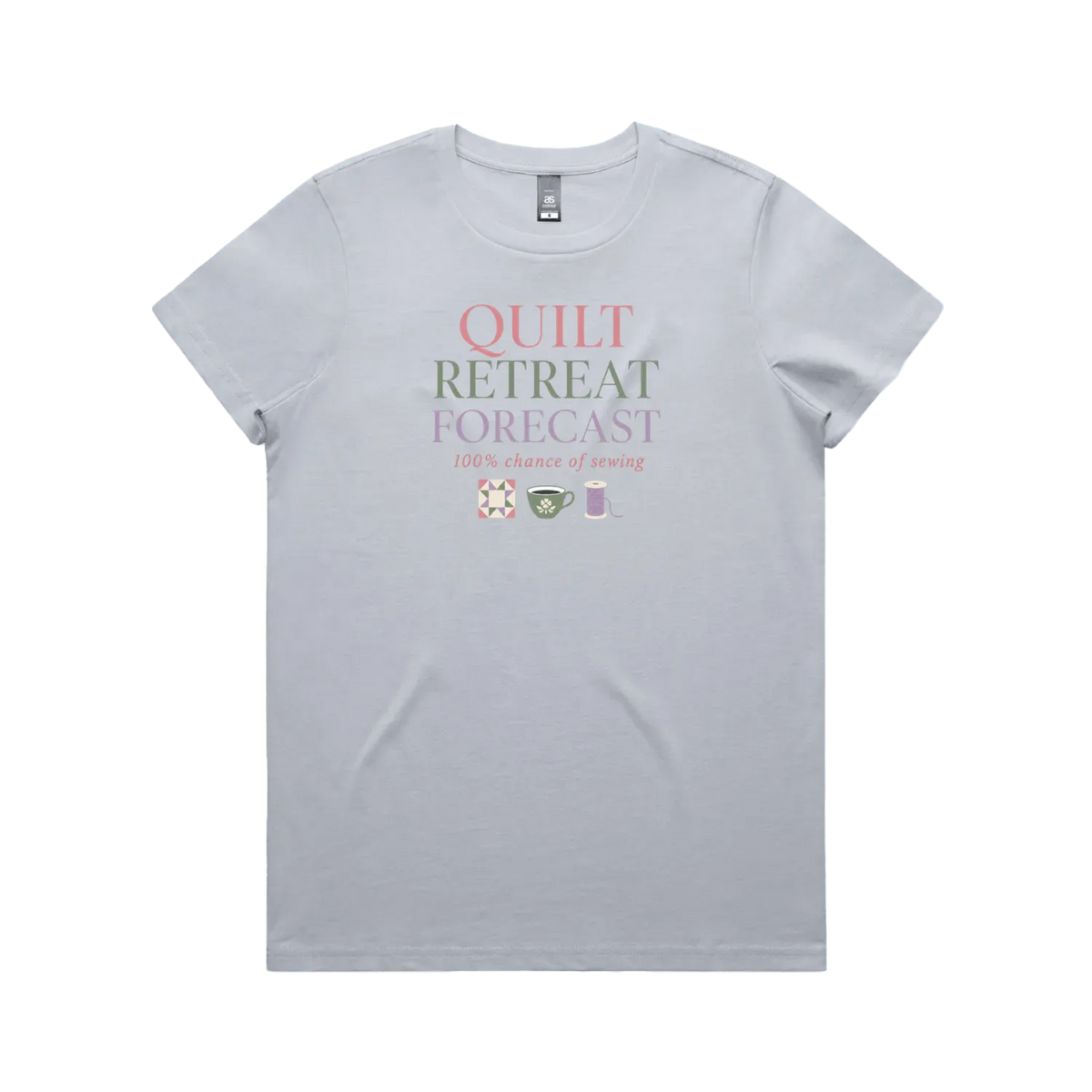 A powder blue short-sleeve crewneck t-shirt featuring a graphic print on the front that reads 'QUILT RETREAT FORECAST, 100% chance of sewing' in pink, green, and white lettering, with small sewing-themed icons below.