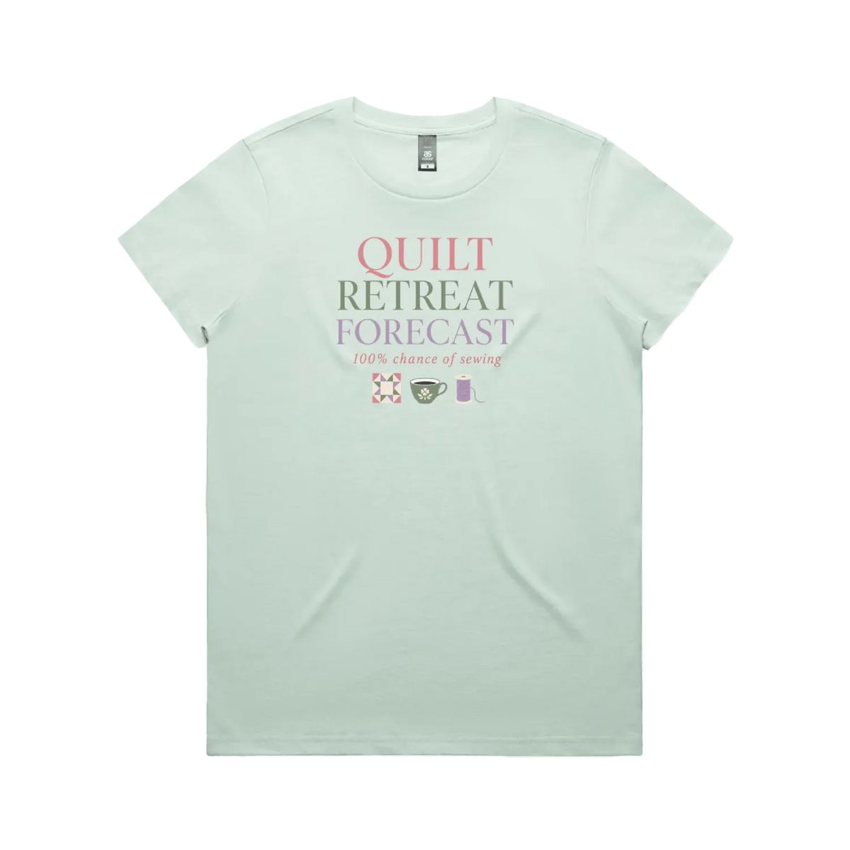 A pale mint green short-sleeve crewneck t-shirt featuring a graphic print on the front that reads 'QUILT RETREAT FORECAST, 100% chance of sewing' in pink, green, and white lettering, with small sewing-themed icons below.