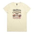 A light butter yellow short-sleeve crewneck t-shirt featuring a retro-style graphic print on the front. The graphic reads 'Quilters Run on Caffeine and Cotton' in stylized fonts, accompanied by illustrations of a fabric stack, a mug of coffee, a pincushion, and a spool of thread.