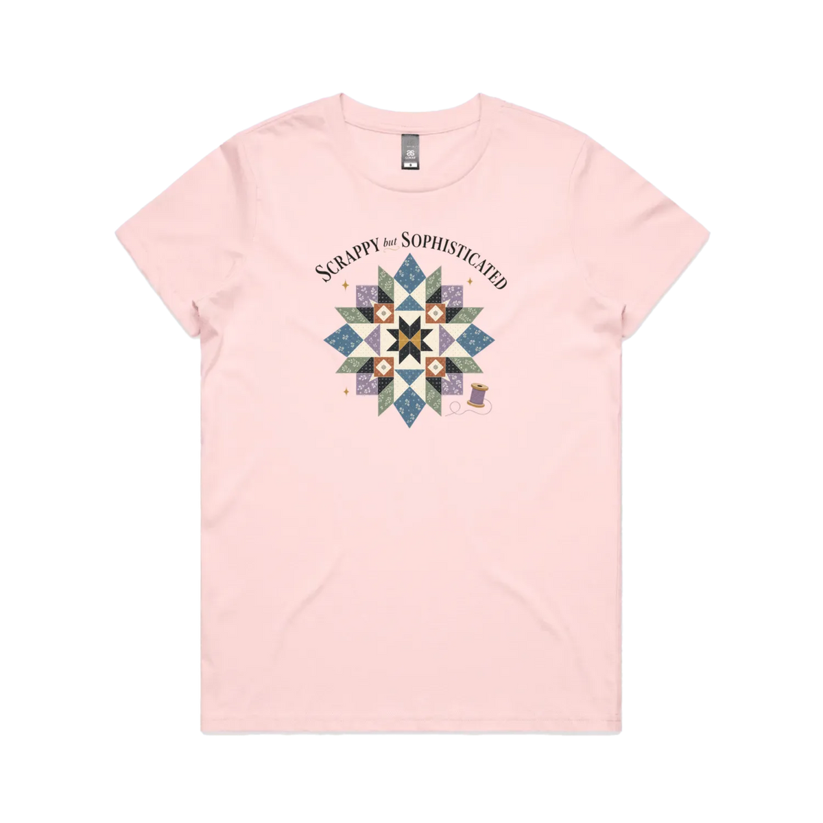 A pale pink short-sleeve crewneck tshirt with the words 'Scrappy but Sophisticated' above a large star quilt block with a purple thread spool on the bottom right.