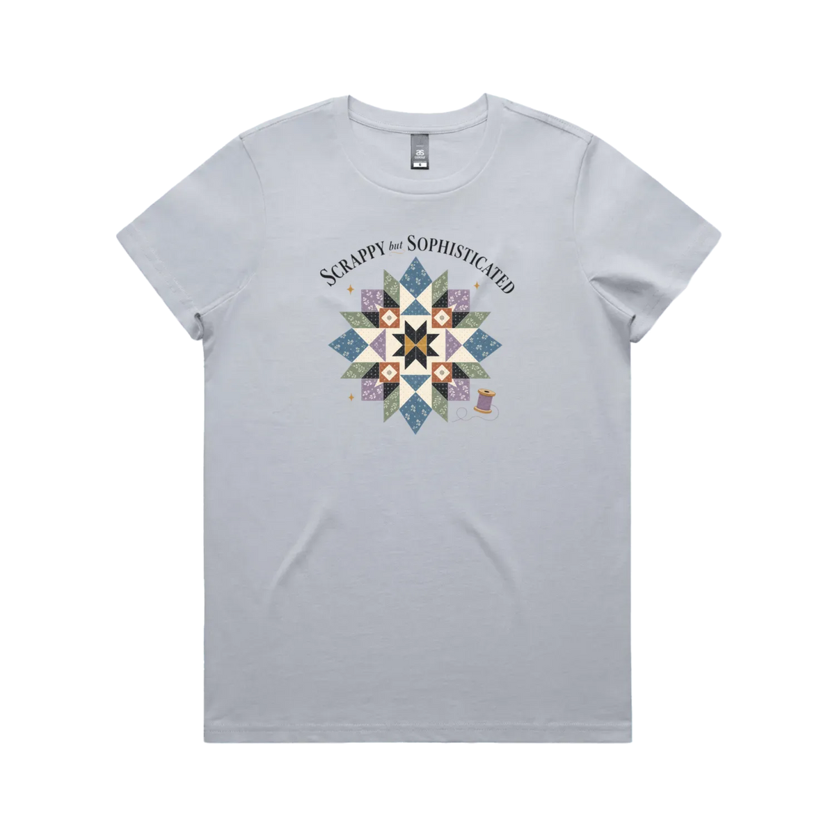 A powder blue short-sleeve crewneck tshirt with the words 'Scrappy but Sophisticated' above a large star quilt block with a purple thread spool on the bottom right.