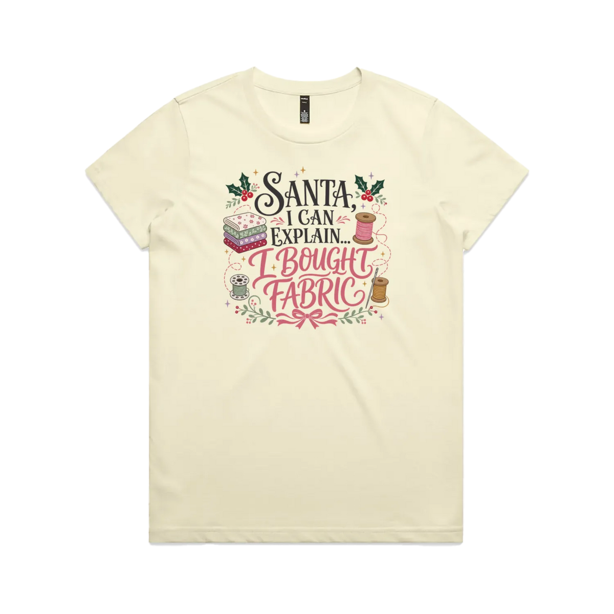 A pale butter yellow short-sleeve crewneck t-shirt with a festive Christmas-themed graphic on the chest. The graphic features the text 'Santa, I Can Explain...I Bought Fabric'.