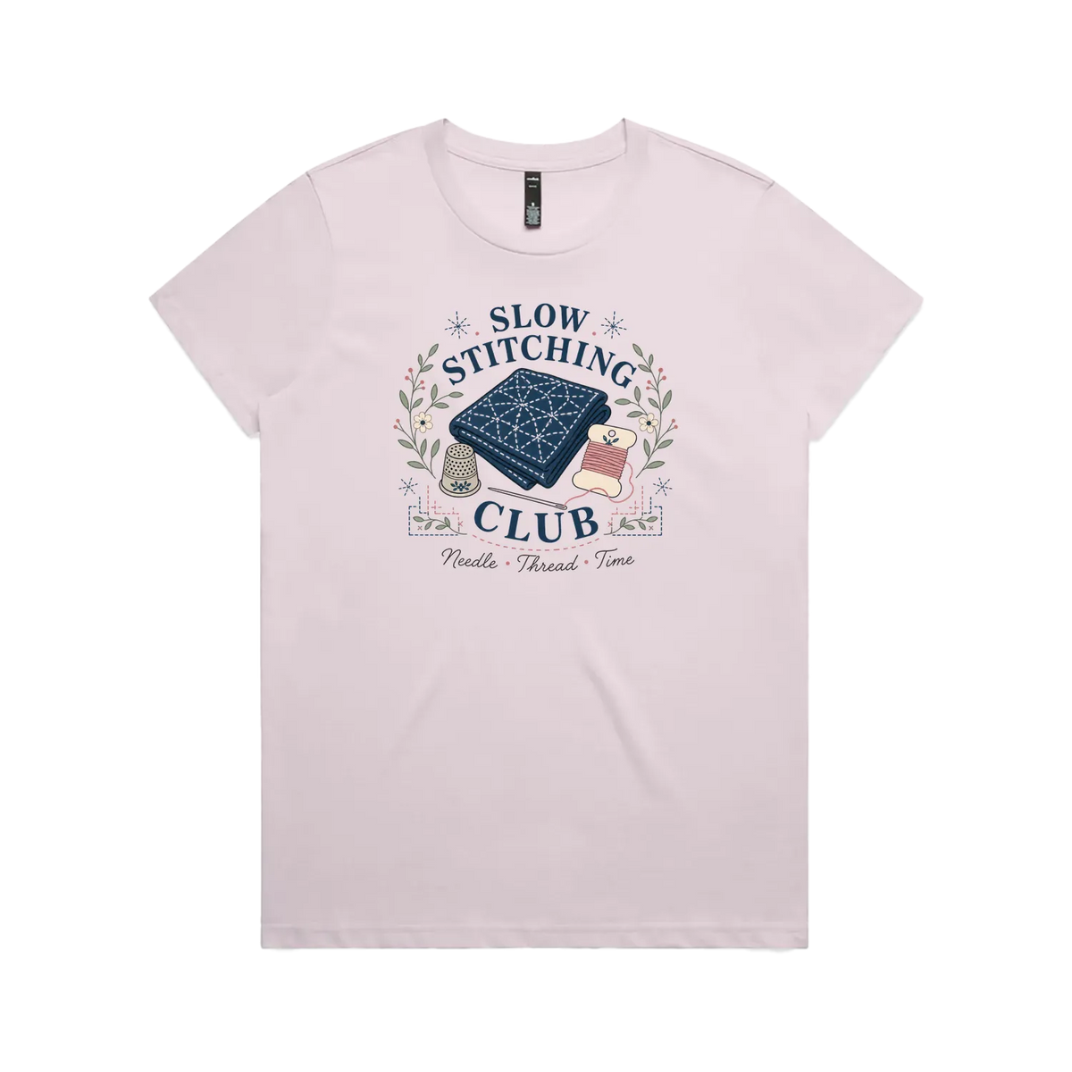A pale mauveshort-sleeved crewneck t-shirt with the graphic 'Slow Stitching Club' surrounding an illustration of a piece of sashiko stitched fabric, thimble, need and thread with small flowers and leaves.