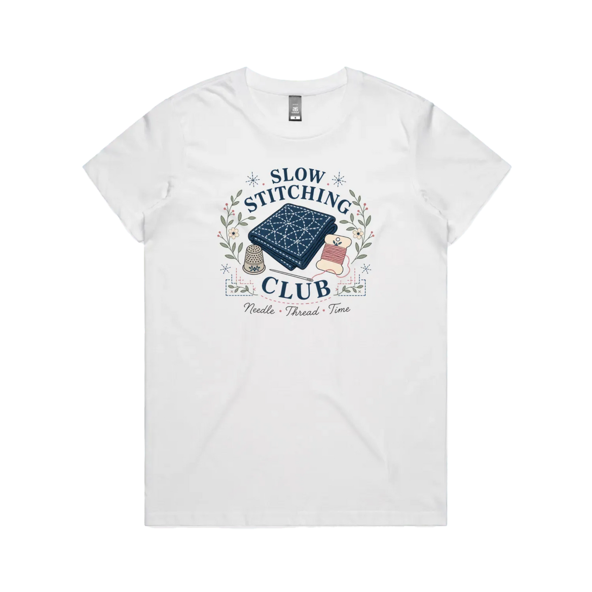 A white short-sleeved crewneck t-shirt with the graphic 'Slow Stitching Club' surrounding an illustration of a piece of sashiko stitched fabric, thimble, need and thread with small flowers and leaves.