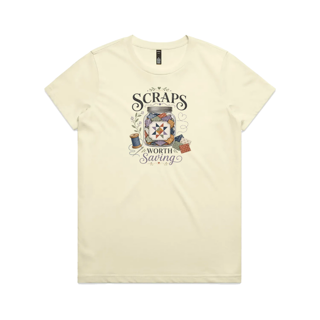 A pale butter yellow short-sleeve t-shirt with the graphic 'Scraps Worth Saving' surrounding a jar filled with small fabric swatches.
