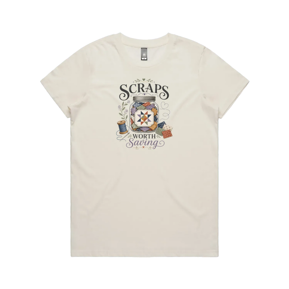 An off-white short-sleeve t-shirt with the graphic 'Scraps Worth Saving' surrounding a jar filled with small fabric swatches.