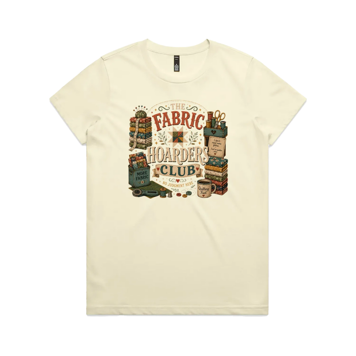 A pale butter yellow short-sleeve crewneck t-shirt with a vintage style graphic featuring the words 'The Fabric Hoarders Club' surrounded by fabric stacks, a coffee mug and quilting tools.