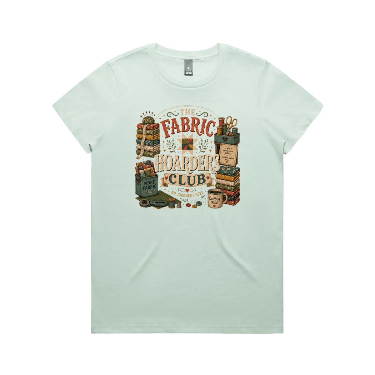 A pale mint green short-sleeve crewneck t-shirt with a vintage style graphic featuring the words 'The Fabric Hoarders Club' surrounded by fabric stacks, a coffee mug and quilting tools.