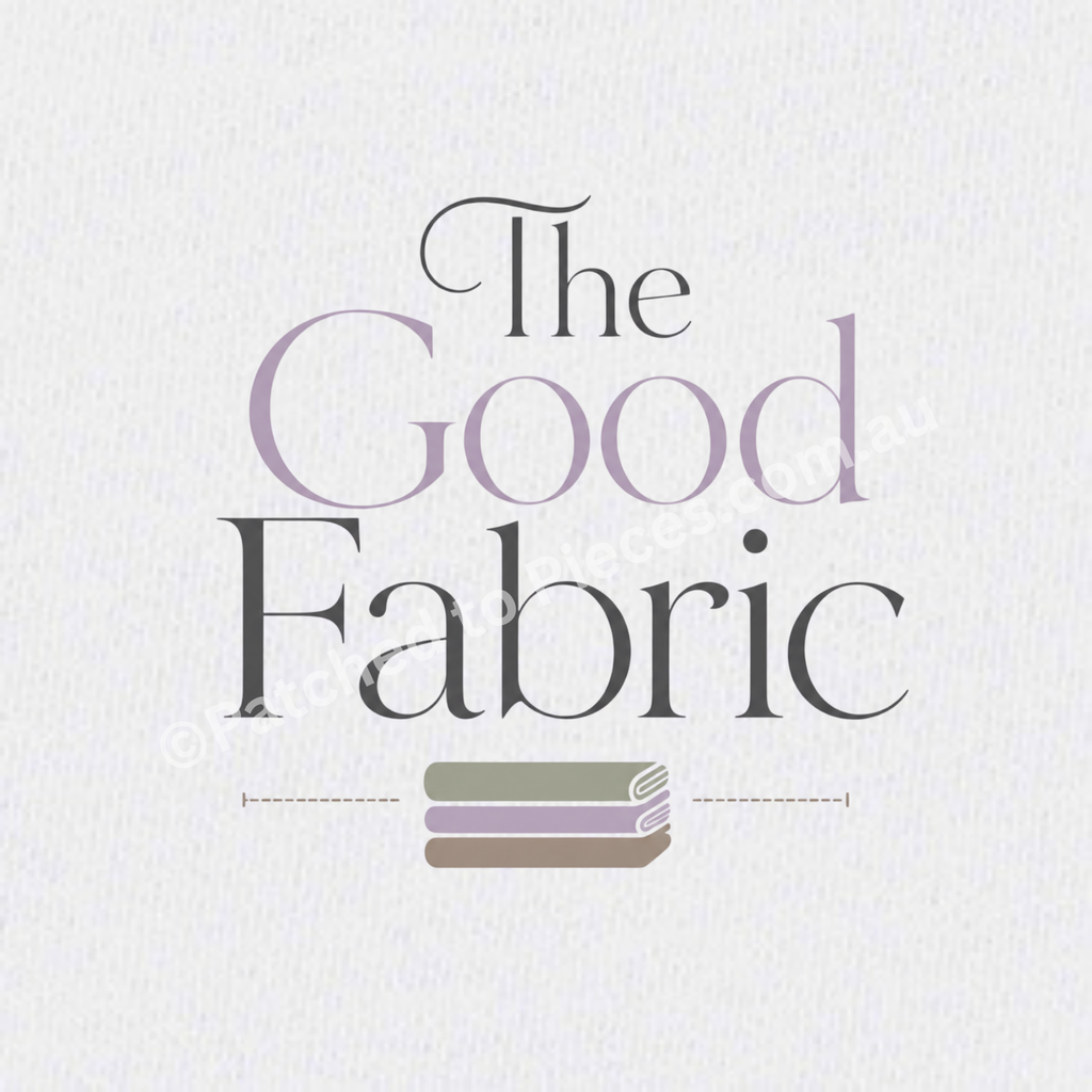 A close-uo of The Good Fabric image centered on a white textured background. The words 'the' and 'fabric' are printed in black with the word 'good' printed in lavender. A stack of folded fabric in sage, lavender and brown sits below the words.