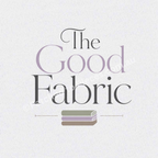 A close-uo of The Good Fabric image centered on a white textured background. The words 'the' and 'fabric' are printed in black with the word 'good' printed in lavender. A stack of folded fabric in sage, lavender and brown sits below the words.