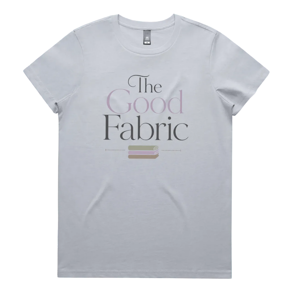 A powder blue short-sleeve crewneck t-shirt featuring a graphic print on the front that reads 'The Good Fabric' in dark gray and lavender lettering, with a small fabric bundle illustration below.