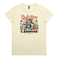 A pale butter yellow short-sleeve t-shirt with a colorful retro graphic on the chest featuring a vintage rotary phone made of fabric pieces, a spool of thread, shopping bags, and the text 'The Quilt Shop Called, I Answered'.