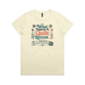 A pale butter yellow short-sleeve graphic t-shirt with the words 'What Happens at Quilt Retreat...ends up in another project bag'. The words are surrounded by quilt blocks thread spools, scissors, a coffee mug and zippered bag.